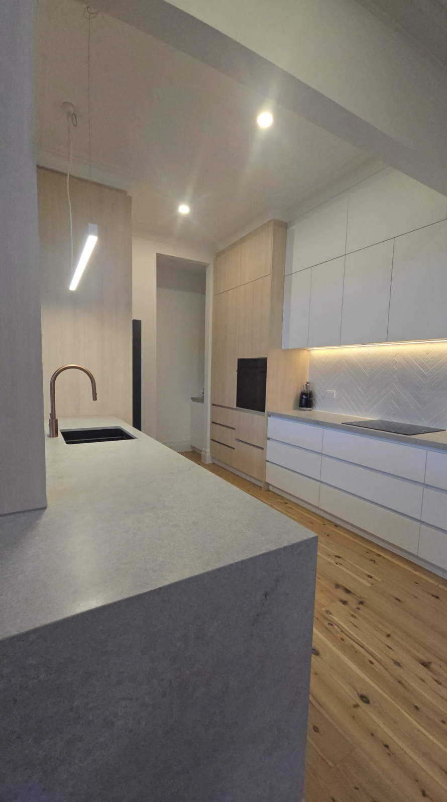 Renovated kitchen with stone island bench, timber joinery and herringbone tiled splashback